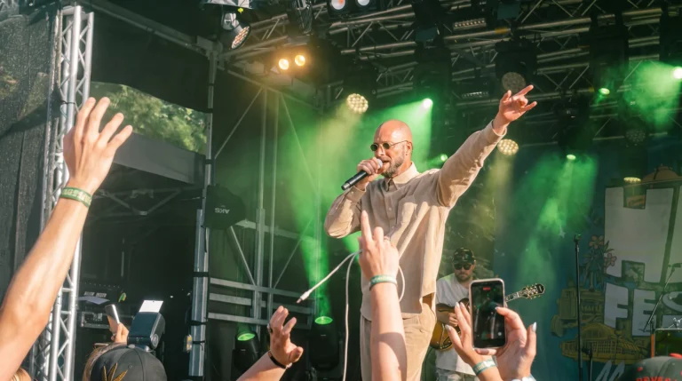 General Knas sjunger på Hampafestivalens scen i grönt ljus medan publiken sträcker upp händerna